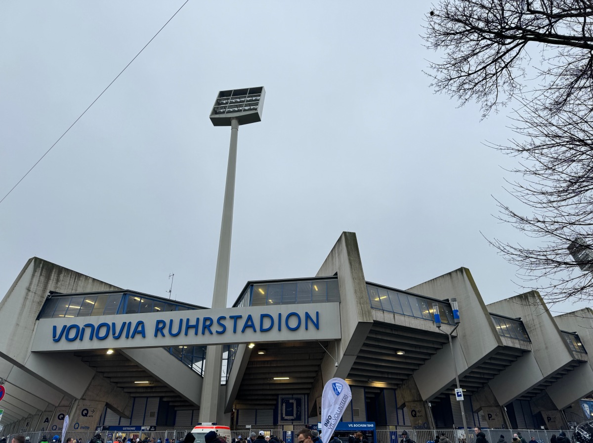 Das Ruhrstadion bei bewölktem Himmel. Der Flutlichtmast ragt aus dem Beton. Vorne die Aufschrift: Vonovia Ruhrstadion.